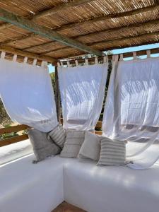 サン・フランセスク・ハヴィエルにあるEncanto y Hadasの白いカーテンと枕が備わる白いベッド