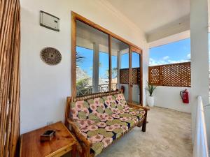 - un salon avec un canapé et de grandes fenêtres dans l'établissement Chikachika Beach B&B, à Nungwi