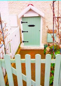 a green door on the side of a fence at Fisherman's Cottage - The Ultimate Romantic Lakeside Cottage just a few steps from the Beach! Relax with a glass of wine & Snuggle up to the Cosy Log Burner at the BEST Location in Mablethorpe! It's Pet Friendly too! in Mablethorpe