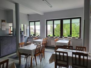 uma sala de jantar com mesas, cadeiras e janelas em Hotelik OSiR Lubawa em Lubawa