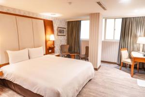 una camera d'albergo con un grande letto e una scrivania di Elegance Hotel a Taipei