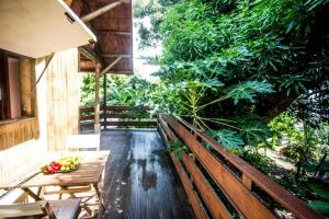 un banco de madera en un porche con un bol de fruta en Shuit Bambou, en La Trinité