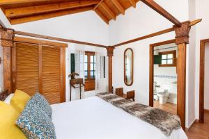 a bedroom with a white bed and a bathroom at Las Casas del Chorro in Agulo