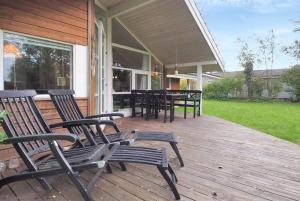 a deck with chairs and tables on a house at Sommerhus i Marielyst m/Spa og sauna - tæt på by og strand in Bøtø By