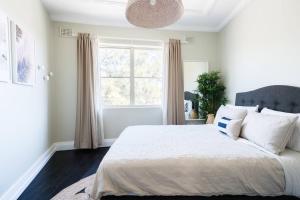 a bedroom with a large bed with a large window at Beautiful 2BR Top Floor Bondi Beach Walk to Beach in Sydney