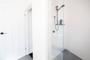 uma casa de banho com um chuveiro e uma porta de vidro em Beautiful 2BR Top Floor Bondi Beach Walk to Beach em Sidney