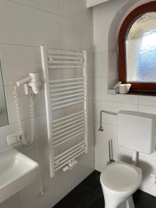 Baño blanco con aseo y lavamanos en Schwaiger, en Breitenbach am Inn