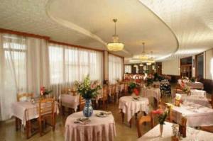 un restaurant avec des tables et des chaises blanches ainsi qu'une salle remplie de tables et de chaises dans l'établissement Hotel Ducale, à Tabiano