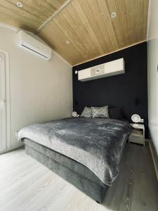 Voralpen Lodge - Ferienhaus mit Gym, Sauna & Hot Tub في Traisen: غرفة نوم بسرير كبير وبجدار اسود
