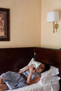 a woman laying in bed with a book at Hotel Petite Fleur in Roccaraso