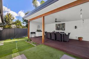 un patio con mesa y sillas en una terraza en Ultra Modern & Relaxing Inner City 4bed House - with a Private Pool - 10mins walk to Beach, en Gold Coast