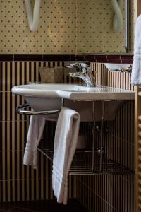 a bathroom with a sink and towels on a shelf at Hotel Petite Fleur in Roccaraso