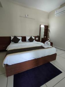 Hotel Crown Inn في دهرواد: غرفة نوم بسرير كبير مع شراشف بيضاء