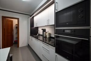 a kitchen with white cabinets and a black microwave at Lido Gardens Funchal in Funchal