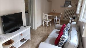 sala de estar con sofá y TV de pantalla plana en Cozy House con Corte Privata in Centro Storico AQ, en LʼAquila