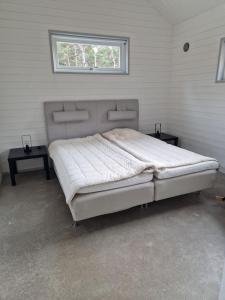 a bed in a room with two tables and a window at Fräscht, spatiöst hus in Visby