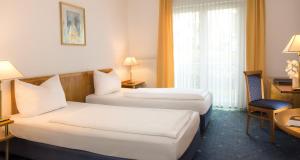 Cette chambre comprend deux lits et un bureau. dans l'établissement Victor's Residenz-Hotel Gummersbach, à Gummersbach