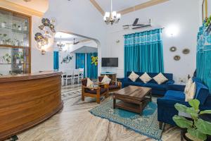 een woonkamer met blauwe meubels en een bar bij GR Stays 4bhk Private Villa with Private Jacuzzi Pool BAGA in Baga