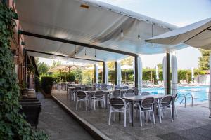 un patio con tavoli, sedie e piscina di Agriturismo La Margherita a Carmagnola