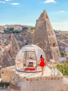 een vrouw in een rode jurk die voor een piramide staat bij Anatelein Boutique Cave Hotel in Uchisar