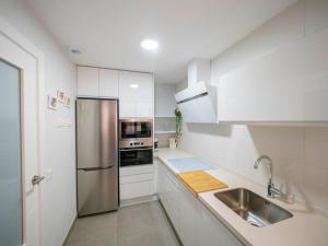 una cucina con armadi bianchi e frigorifero in acciaio inossidabile di Home Luxury fjHomefj a Jerez de la Frontera