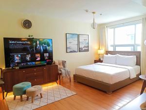 DasagSpacious 36sqm Studio with 65" TV Netflix Karaoke and Pool Access Near Airport and Samal Ferry的一间卧室，里面有一张床和一台平板电视