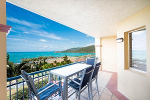 a balcony with a table and chairs and the ocean at Point Break On Airlie in Airlie Beach
