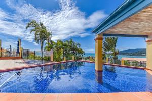 a large swimming pool with a view of the ocean at Point Break On Airlie in Airlie Beach +12 photos