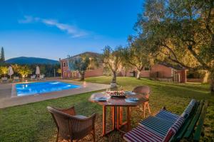 a table and chairs in a yard with a pool at Doliva Estate in Laganas