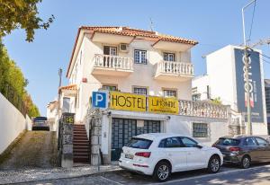 una macchina bianca parcheggiata di fronte a un edificio di Eco Ljmonade Hostel a Cascais