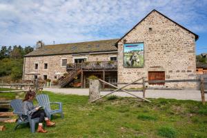 a woman sitting in a chair in front of a building at Logis Les Granges de Bigose in Rimeize