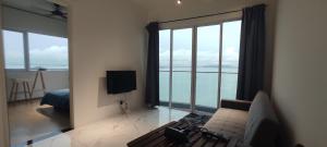 sala de estar con sofá y ventana grande en Infinite Seaview with Penang Bridge Suite with Sunrise up to 11 person en Bayan Lepas