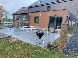 a grill sitting on a patio in front of a building at Le Reposoir Maison spacieuse avec feu au bois in Bertogne