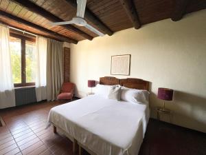 カルマニョーラにあるAgriturismo La Margheritaのベッドルーム(白い大型ベッド、ランプ2つ付)