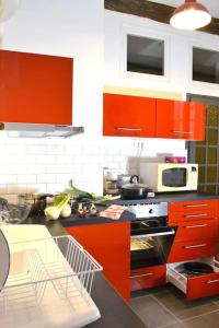 a kitchen with red cabinets and a stove top oven at Apprt Top Center / 2 Chambres / 2 Salles de bain. in Montpellier