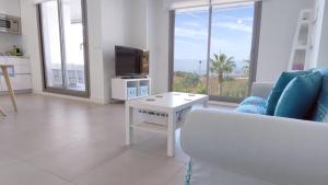 a living room with a couch and a tv and a table at Panorama Beach - Blue Horizon in Torrox Costa