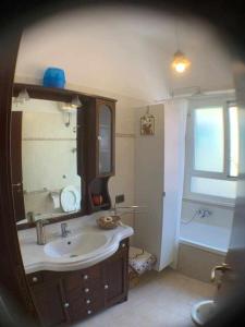 ein Badezimmer mit einem Waschbecken, einem Spiegel und einer Badewanne in der Unterkunft Appartamento sul porto Nettuno in Nettuno