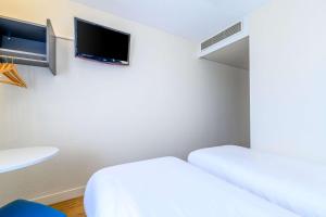 Cette chambre comprend 2 lits et une télévision à écran plat. dans l'établissement Comfort Hotel Paris Porte d'Ivry, à Ivry-sur-Seine