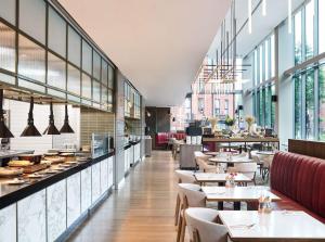 a restaurant with tables and chairs and windows at Hyatt House Manchester - Aparthotel in Manchester