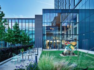 a building with chairs and a statue in front of it at Hyatt House Manchester in Manchester