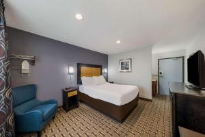 a hotel room with a bed and a blue chair at Quality Inn - Denton in Denton