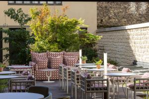un patio al aire libre con mesas, sillas y plantas en Quinzerie hôtel, en París
