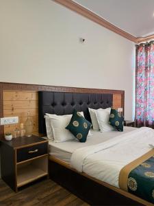 a bedroom with a large bed with green pillows at zikzik holidays in Leh