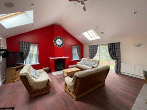 een grote woonkamer met rode muren en meubels bij Belton House Holiday Home in Wanlockhead