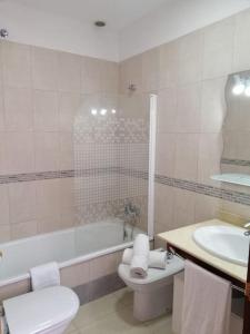 een badkamer met een bad, een toilet en een wastafel bij Idílico adosado en El Mocanal in Mocanal