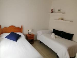 2 camas en una habitación de color blanco y azul en Idílico adosado en El Mocanal en Mocanal