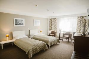a hotel room with two beds and a table and chairs at Villa Helvetia in Târgu-Mureş