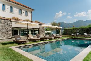 a pool with chairs and umbrellas next to a house at MUSA Lago di Como in Sala Comacina