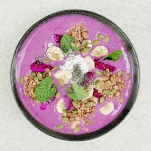 a pink bowl of food with nuts and berries at Surf & Party - Hostel Somewhere Else in Canggu