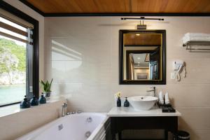 a bathroom with a tub and a sink and a mirror at Hermes Cruises in Ha Long